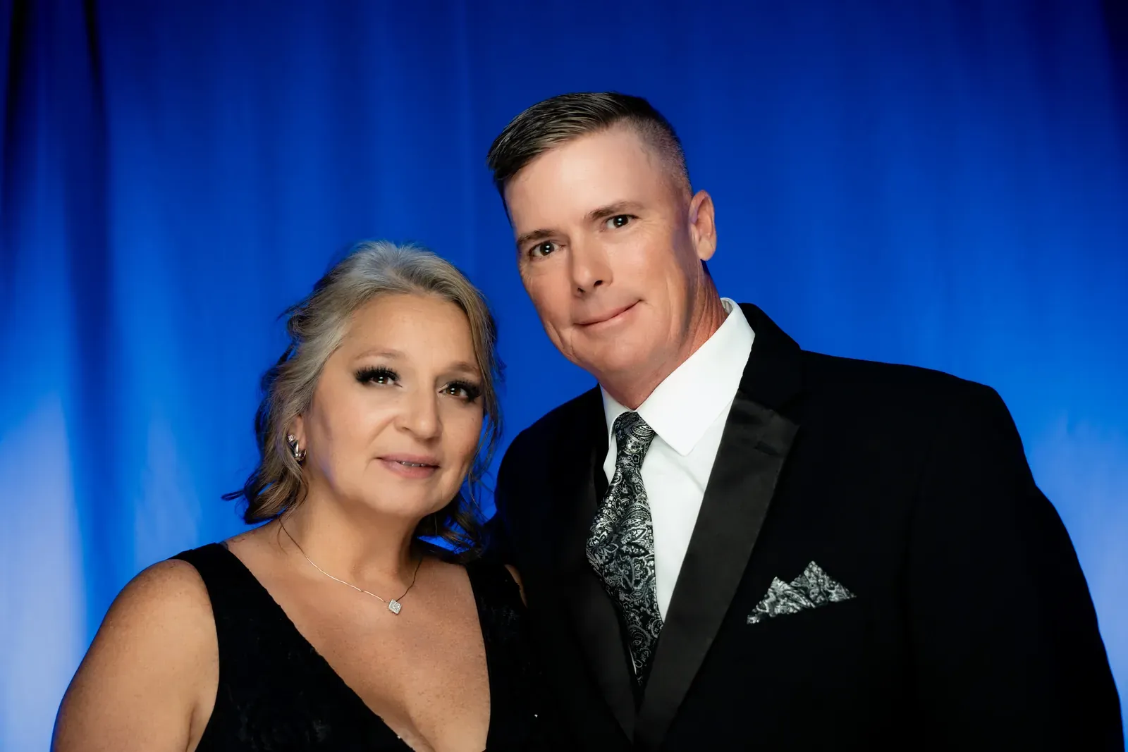 Couple posing beneath chandeliers with ornate masks.