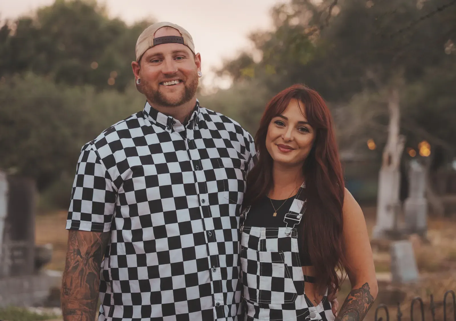 Friends carving pumpkins while warm string lights glow overhead.