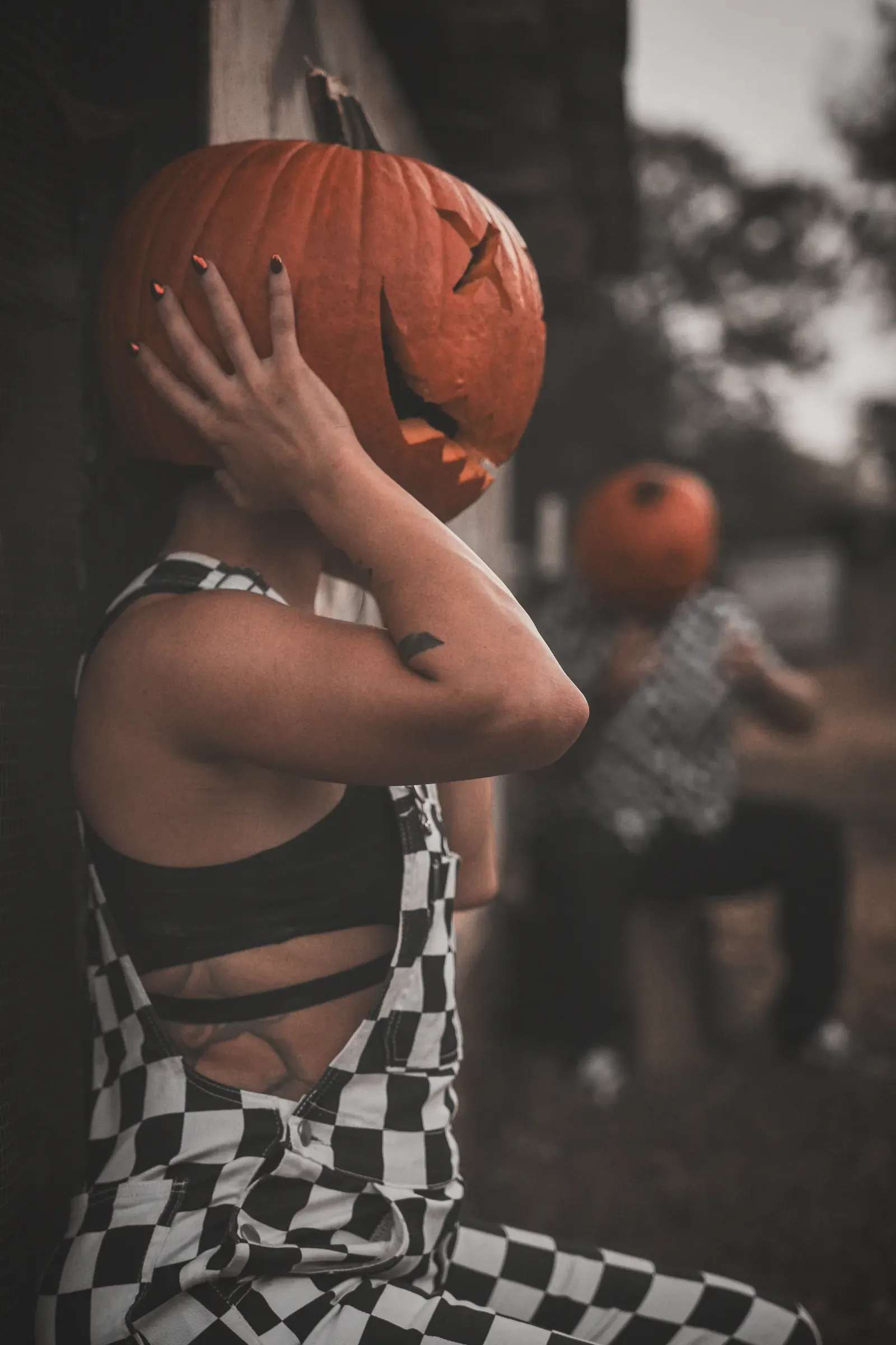 Duo laughing while walking through a pumpkin field.